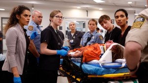 A group of doctors, nurses, and police officers around a body on a gurney; still from 'The Pitt'
