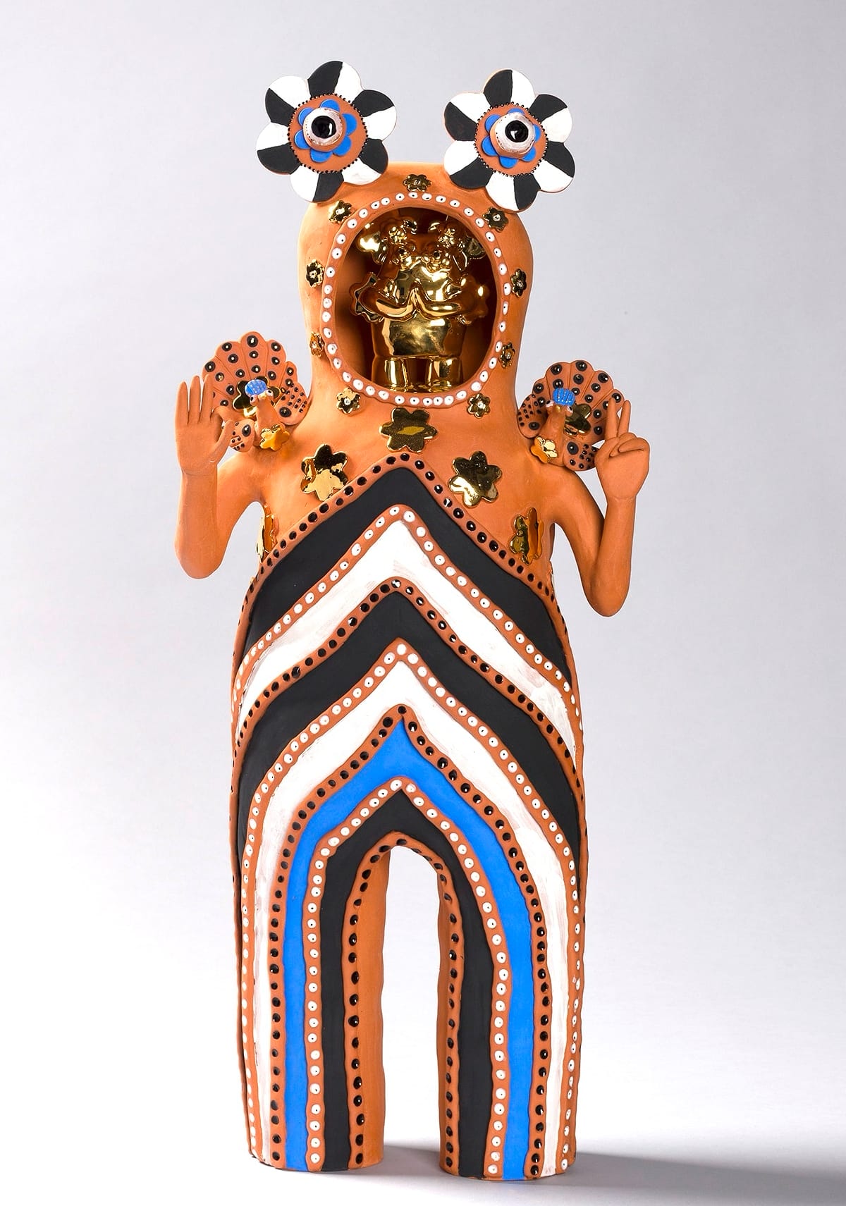 a terracotta figure with white, black, and blue stripes on its body and a gold object for a head