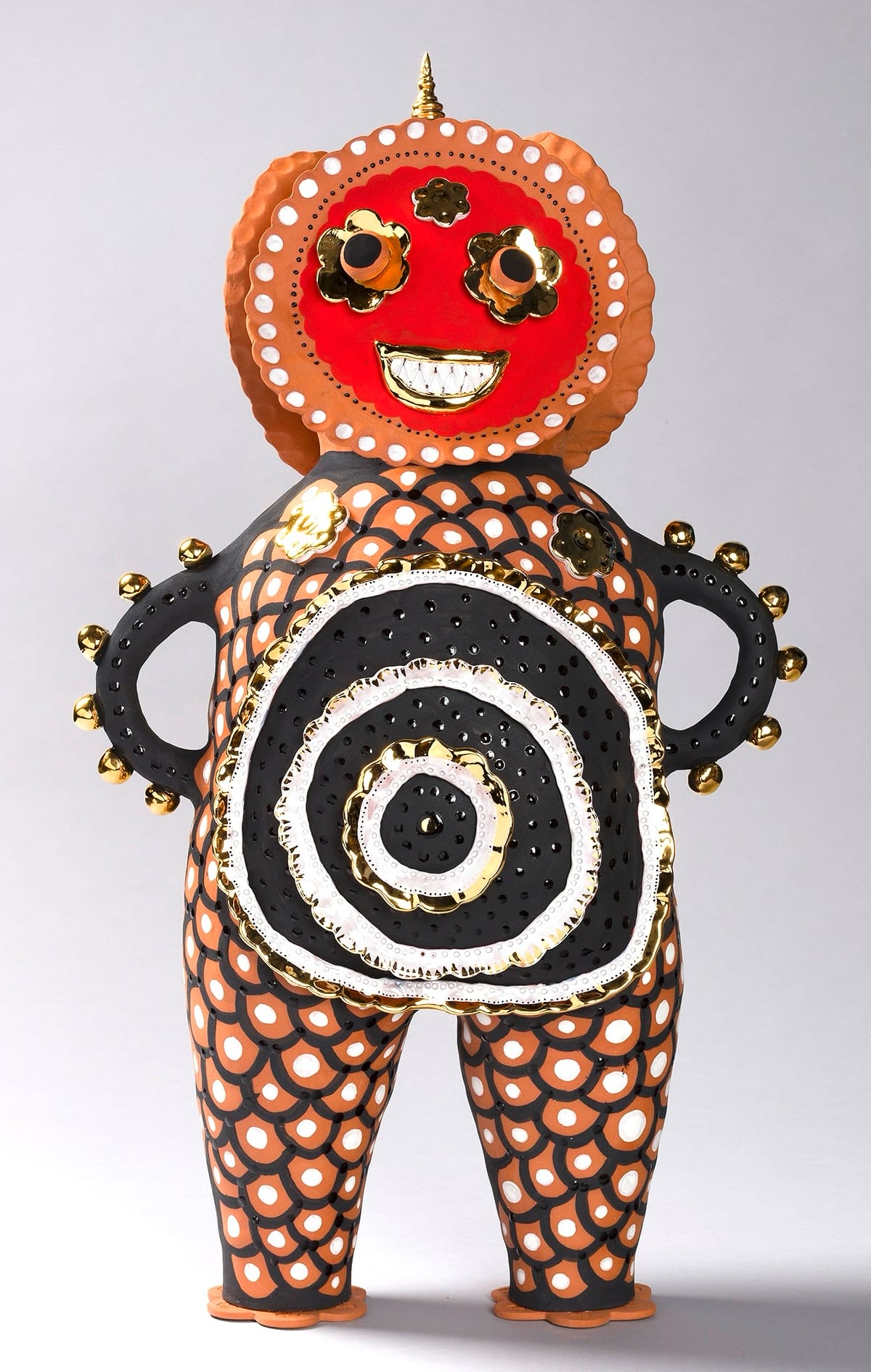 a terracotta figure with black drawings on its body, arms on its hips, and a bright red smiling face