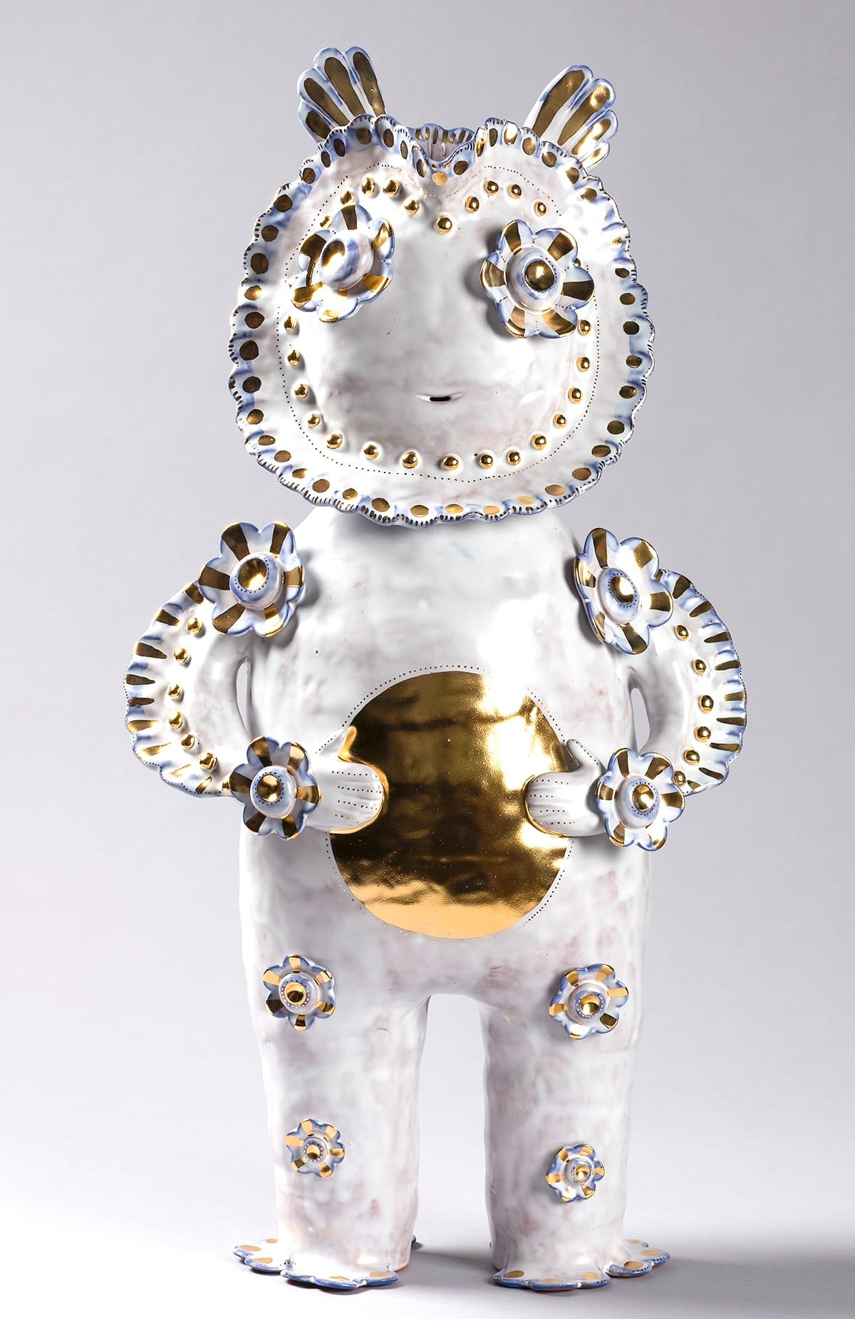 a white figure with patterns on its body and a gold sphere in its hands