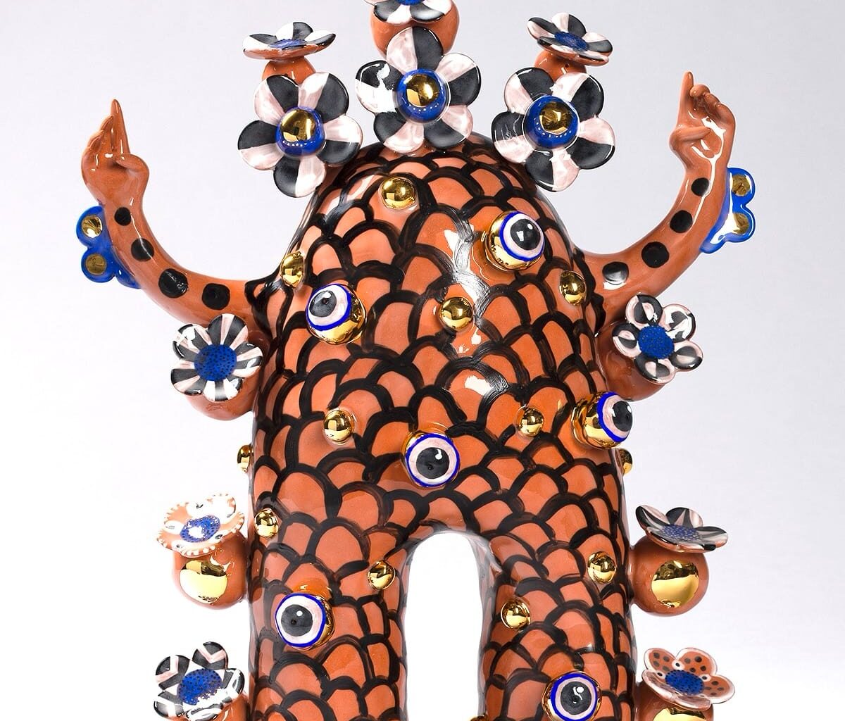 a terracotta figure with flowered patterns and peace sign hands