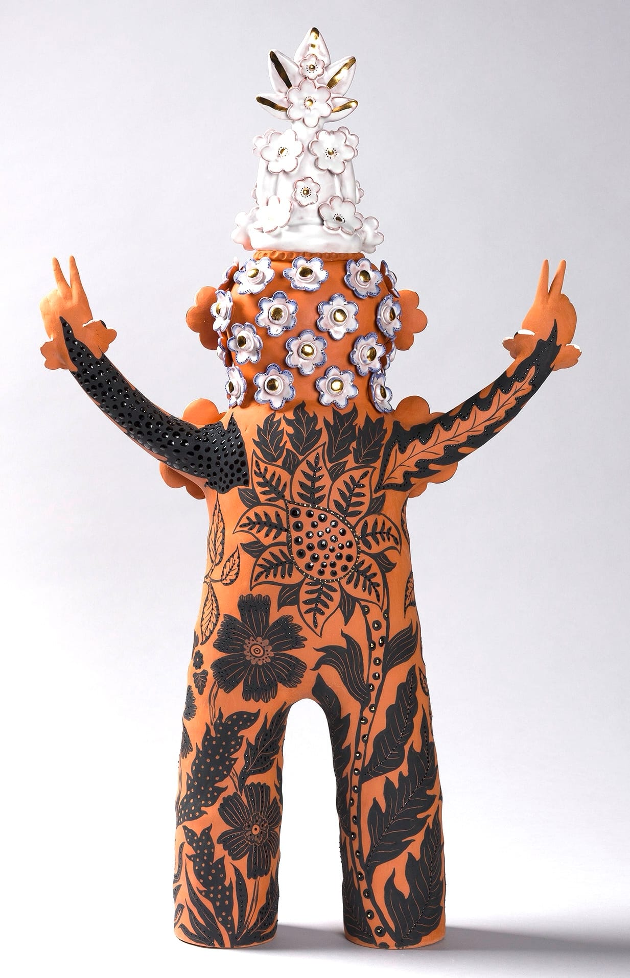 a terracotta figure with flowered patterns and peace sign hands
