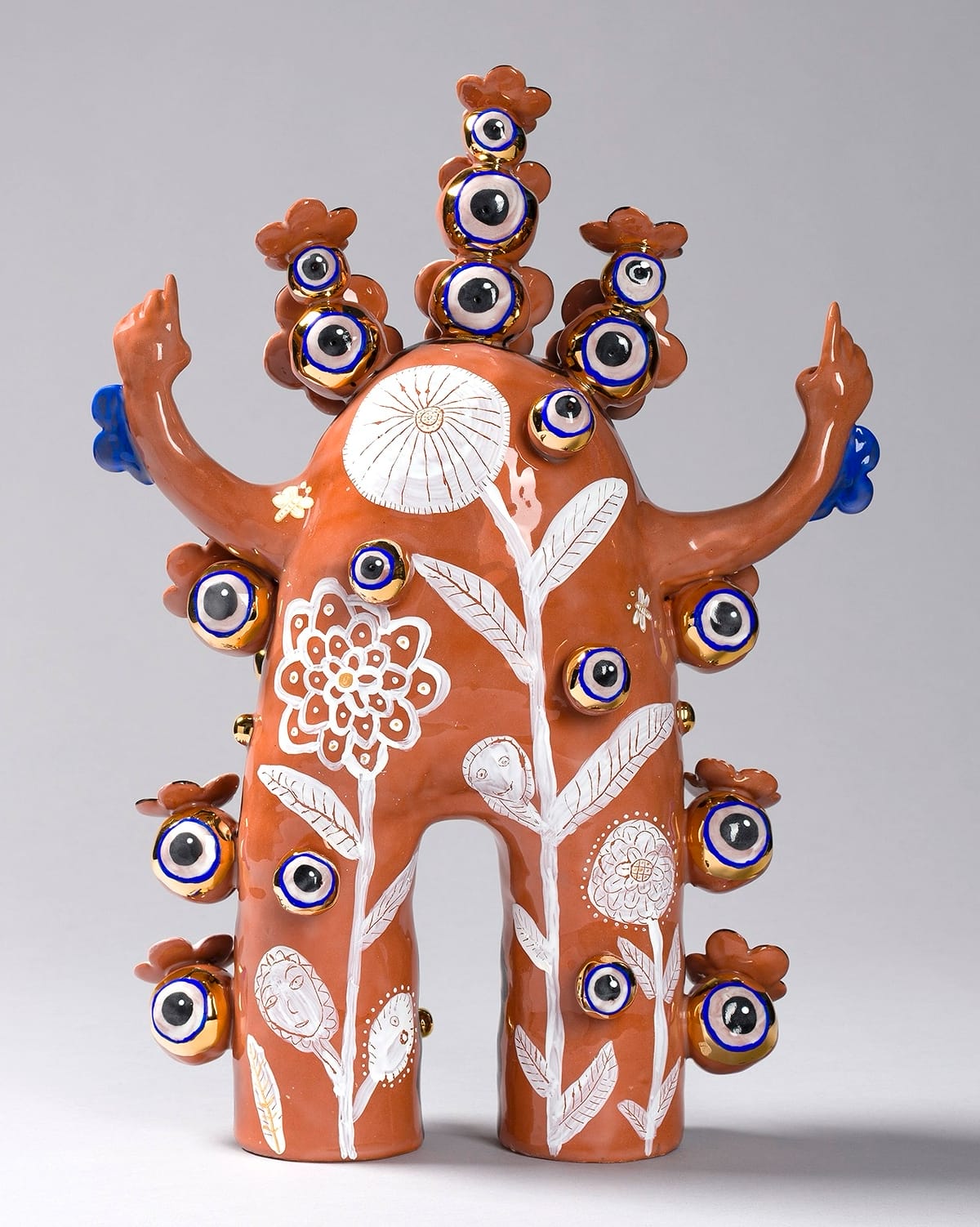 a terracotta figure with flowered patterns and peace sign hands