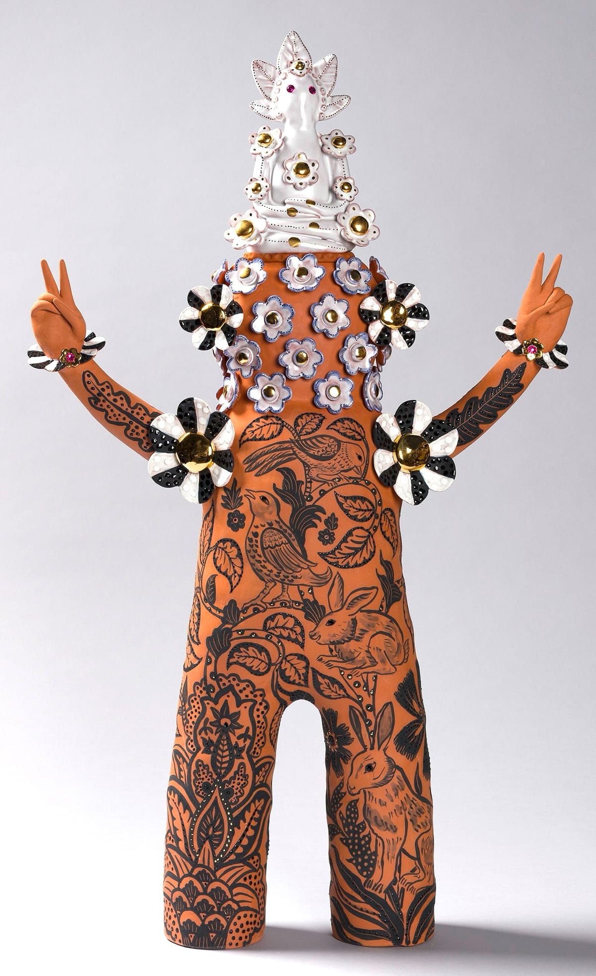 a terracotta figure with flowered patterns and peace sign hands