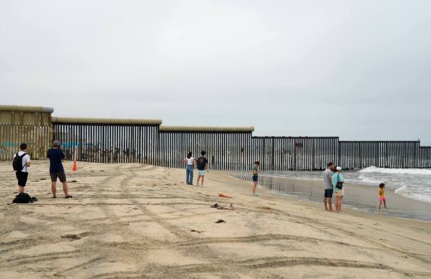 Visitors gather on the U.S. side of the border fence at Border Field State Park on Sunday. (Alejandro Tamayo / The San Diego Union-Tribune)