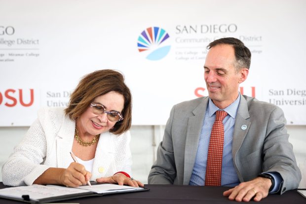 San Diego State University President Adela de la Torre and SD Community College District Chancellor Gregory Smith sign an educational partnership during a press conference in the parking lot of Snapdragon Stadium on Thursday, July 17, 2025 in San Diego, CA. (Meg McLaughlin / The San Diego Union-Tribune)