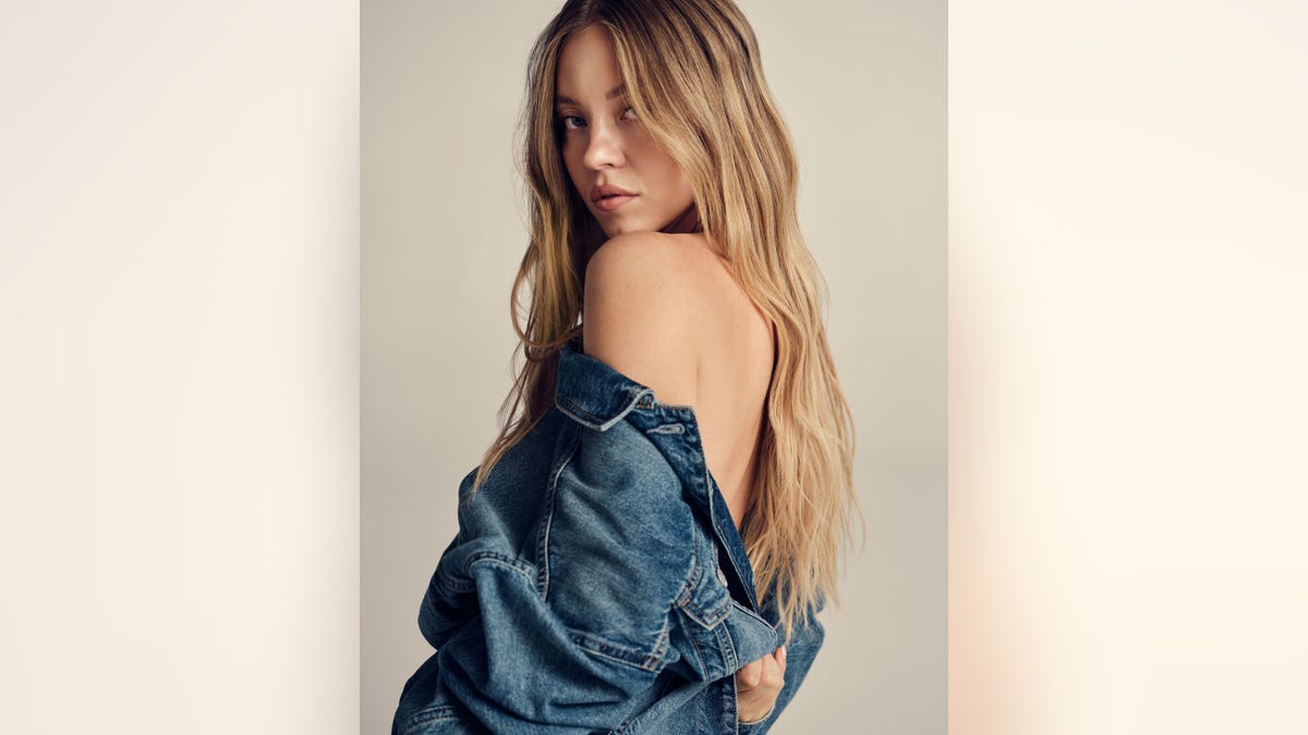 Sydney Sweeney with a jeans jacket slung over her shoulder