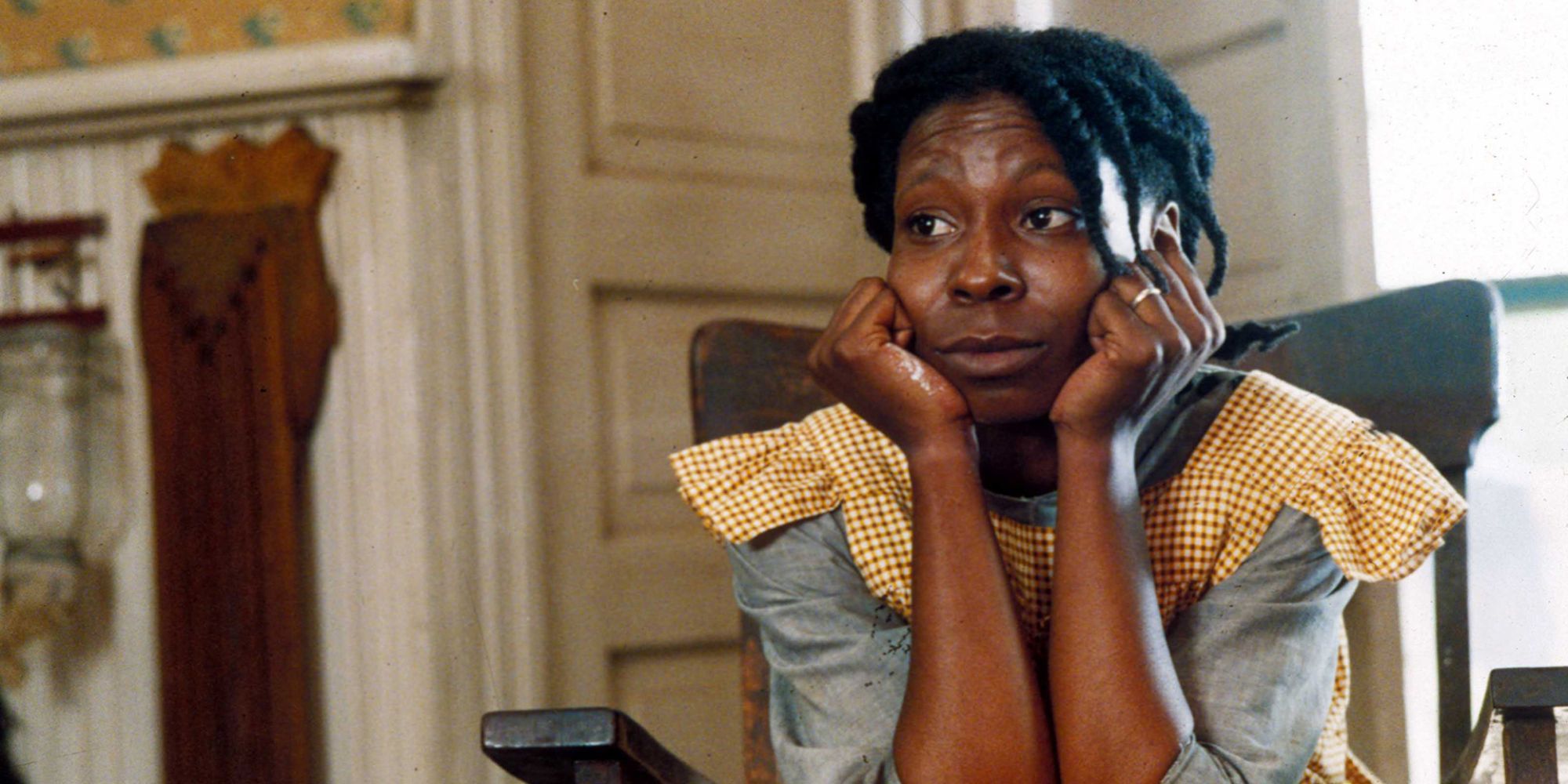 Celie, played by actor Whoopi Goldberg, sits with her chin in her hands in The Color Purple.