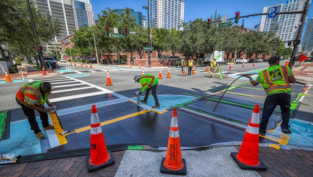 Contractors cover art on the crosswalk at the intersection of South Rosalind Avenue and East Jackson Street in Downtown Orlando, on Wednesday, Aug. 27, 2025. (Ricardo Ramirez Buxeda/Orlando Sentinel)