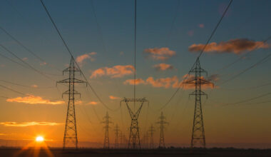 Two rows of power lines are seen in a orange and blue sunrise.