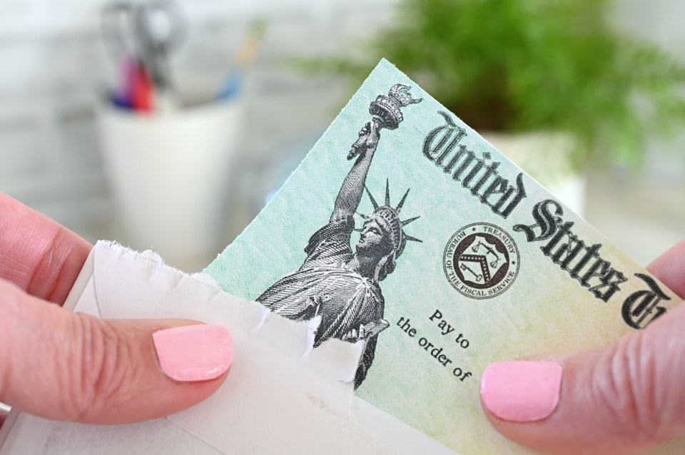 A partially torn United States Treasury check being opened.