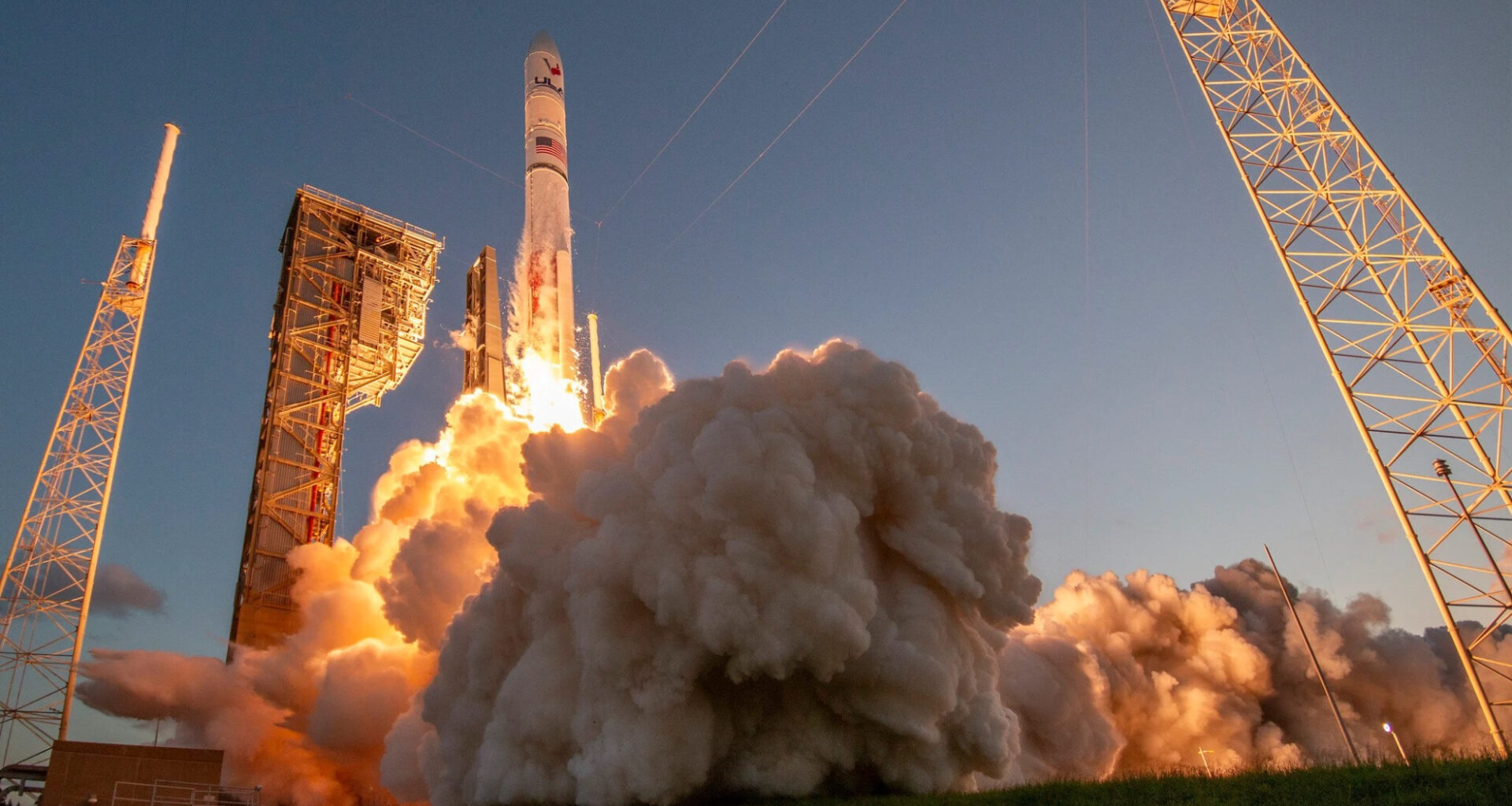 ground-level view of a large white rocket launching into a clear sky