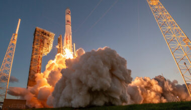 ground-level view of a large white rocket launching into a clear sky
