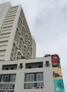 A tall building with a smaller structure in the foreground with murals painted on the corner.