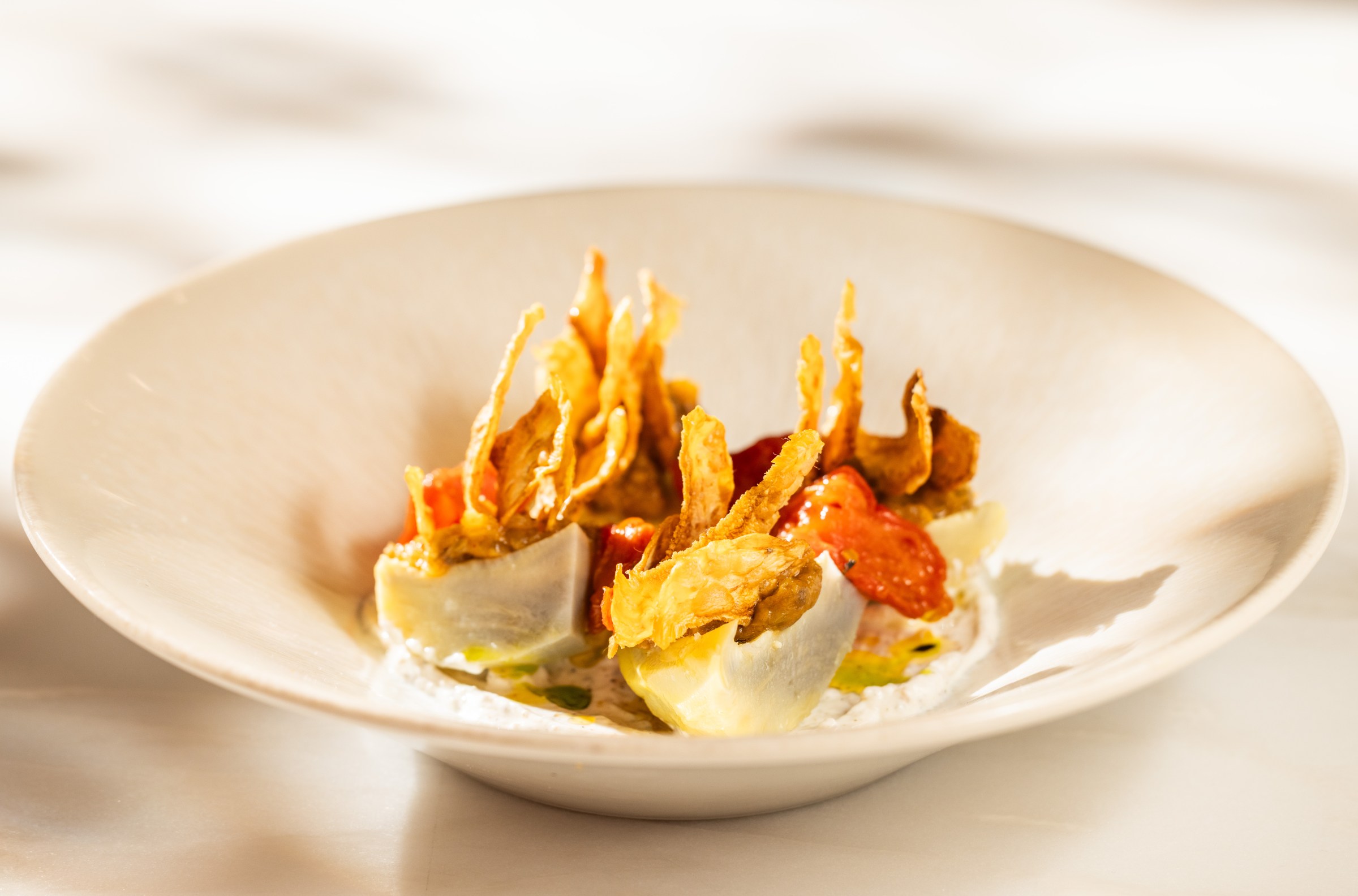 Artichoke salad in a bowl with za’atar yogurt, confit tomato, and mint.