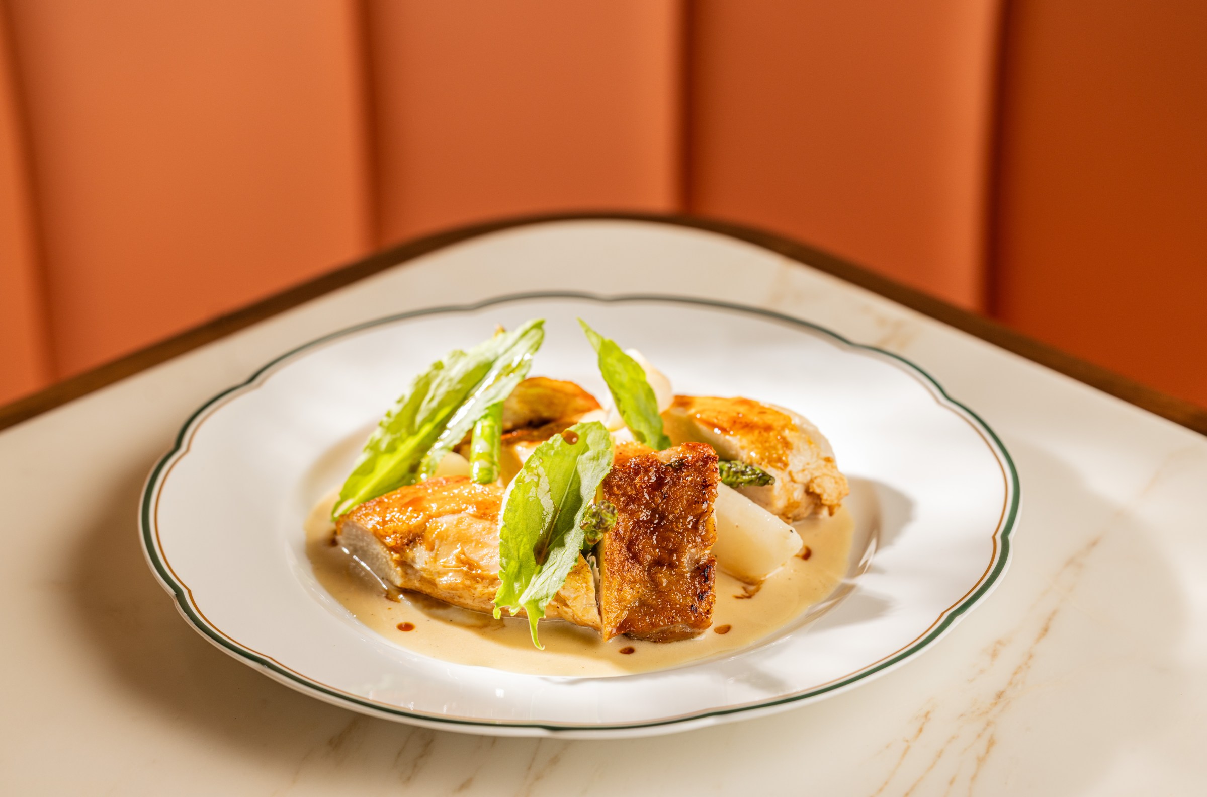 Jidori chicken on a plate with turnips, sunchoke, and vin jaune sauce.