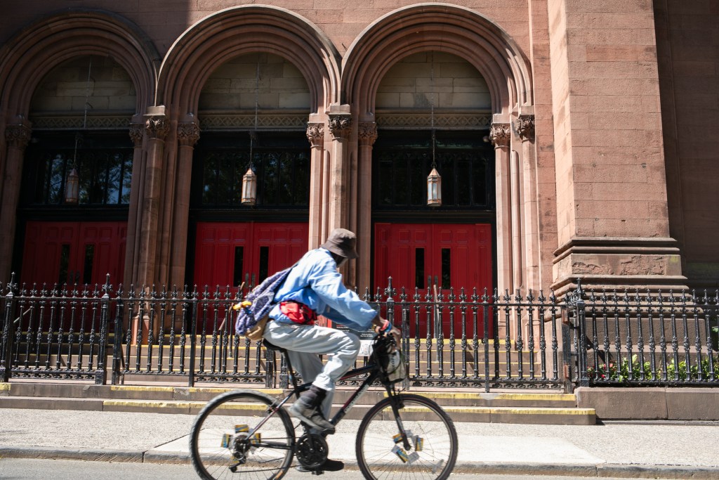 A man rides a bike pas the front steps of St. George's Church.