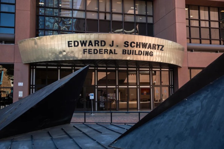Entrance of the Edward J. Schwartz Federal Building with a metal awning and glass doors, featuring nearby dark metallic sculptures.