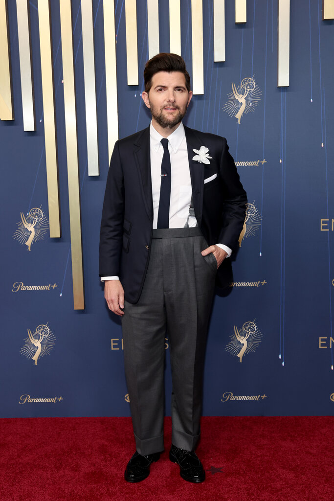 A man wears a navy suit coat and matching tie with gray slacks.