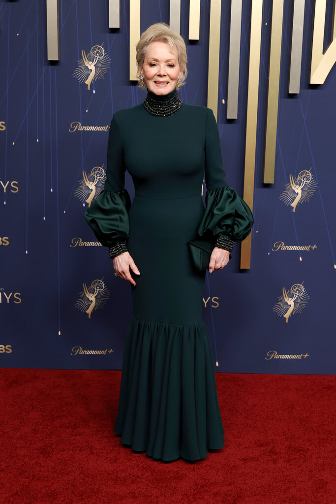 A woman wears a green dress with balloon sleeves and a high neck.