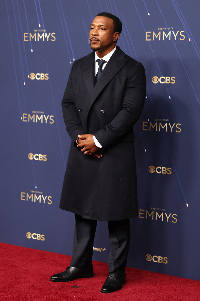 A man wears a navy suit and matching overcoat.