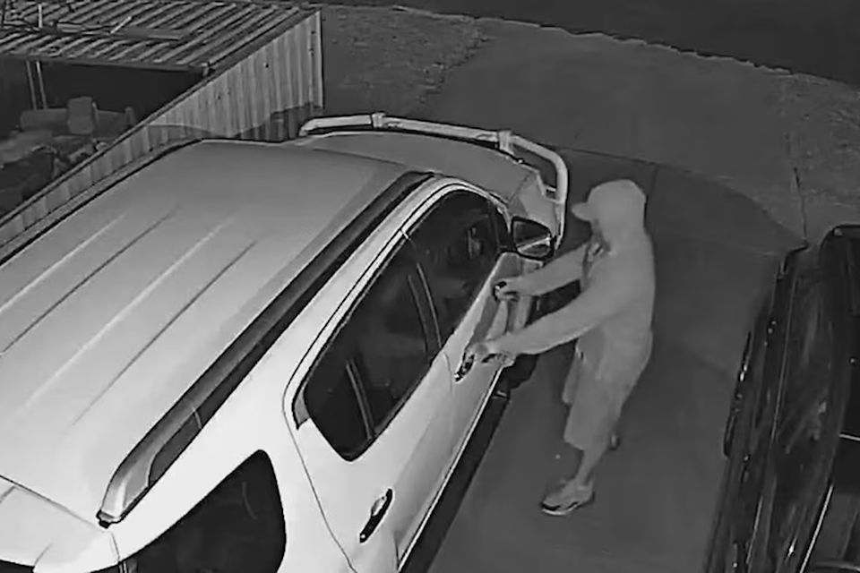 A hooded figure attempts to steal a vehicle in a driveway. 