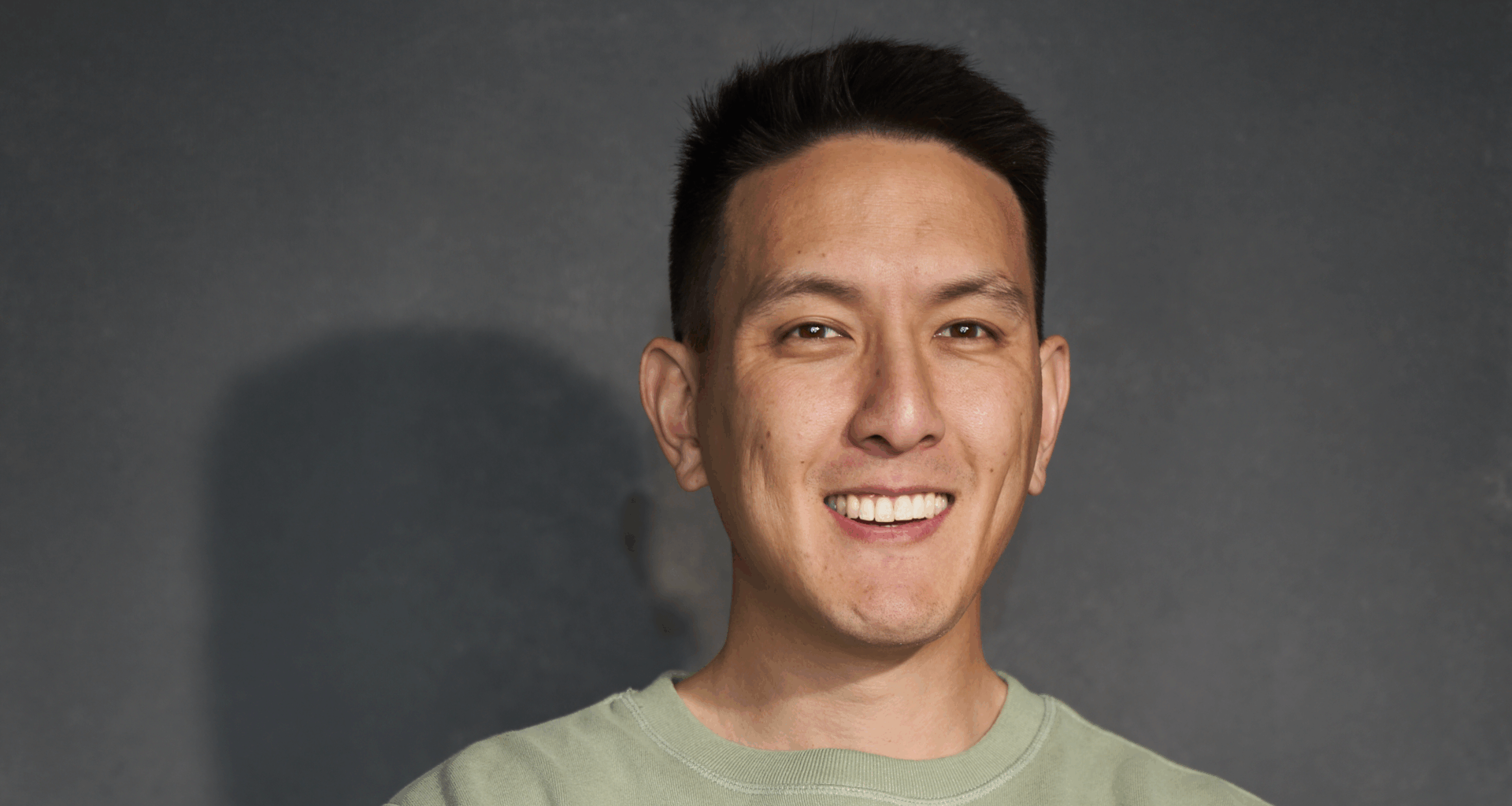 Humphrey Yang smiling in front of a grey backdrop