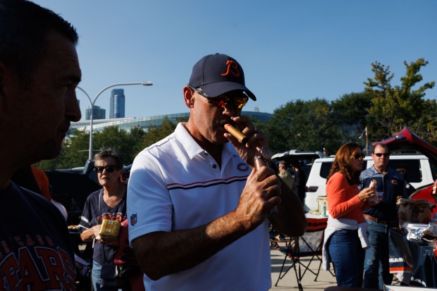 Tim Rose lights a cigar while tailgating outside Soldier Field...