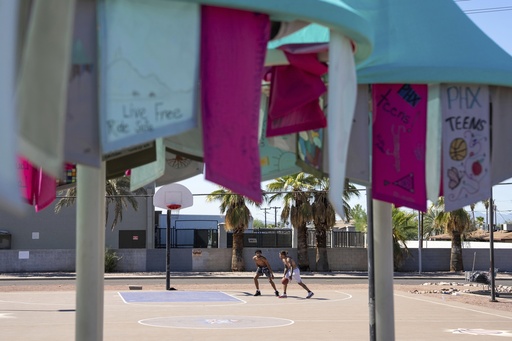 Edward Shephard, left, and Adrian Simpson play basketball near a temporary public art piece that provides shade at Sunnyslope Park in Phoenix, Saturday, Aug. 30, 2025. (AP Photo/Samantha Chow)
