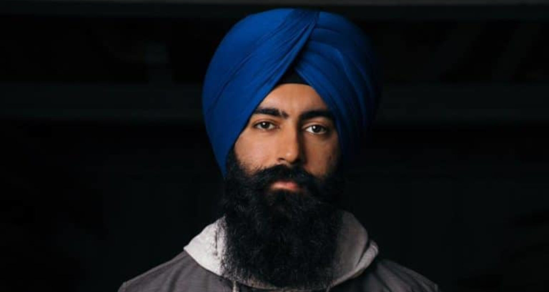 Jaspreet Singh looking into the camera with a serious expression, on a black background.