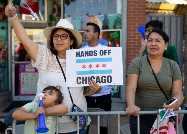 People hold a sign while watching the annual 26th Street Mexican Independence Day Parade on Sept. 14, 2025, in Chicago's Little Village neighborhood. (Brian Cassella/Chicago Tribune)