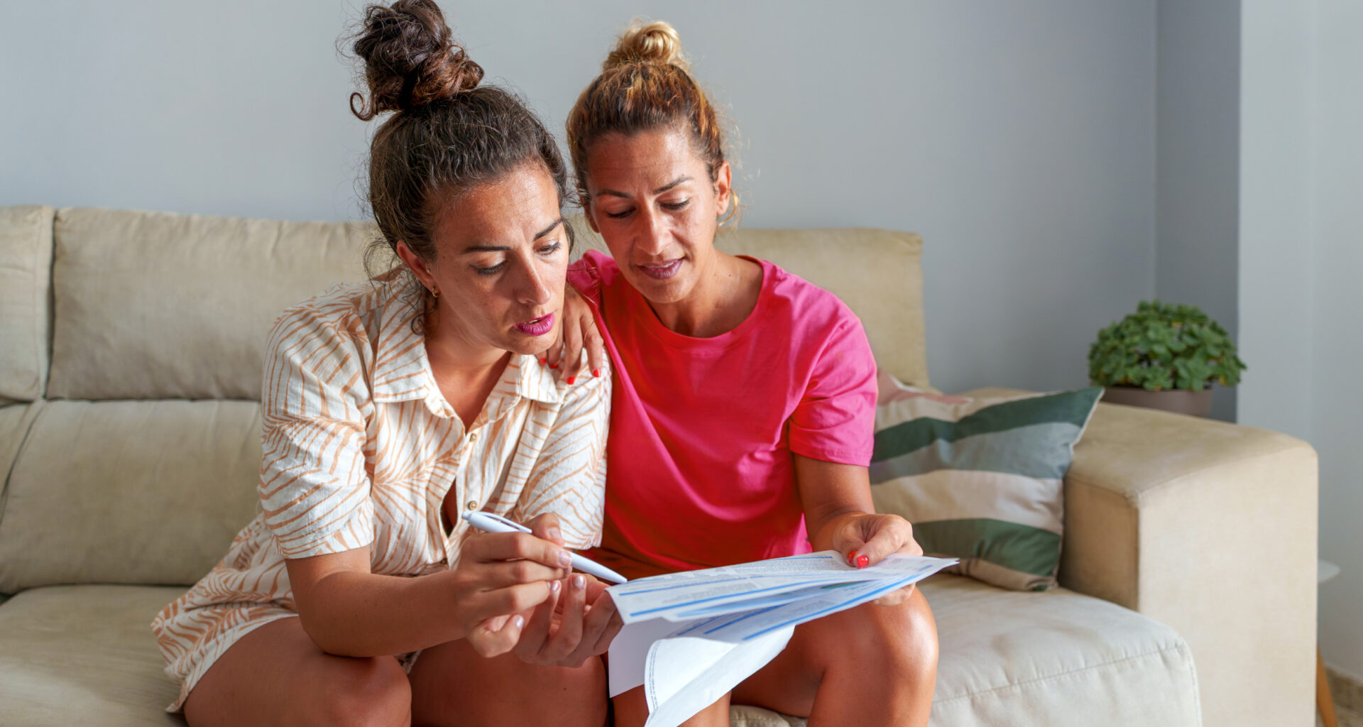 Women looking at bills on a couch.