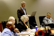 City Council member Chad West, standing, takes notes on his laptop as his colleagues are...