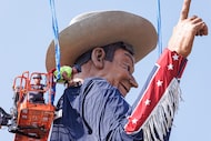 Workers take off cables during the raising of Big Tex at the Fair Park in Dallas, TX on...