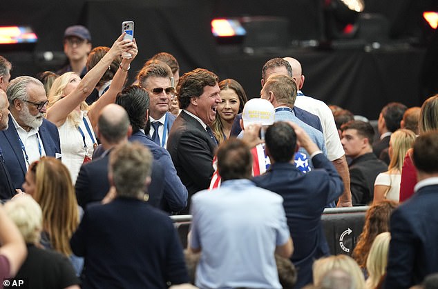 Tucker Carlson, center, attends a memorial for conservative activist Charlie Kirk, Sunday, Sept. 21, 2025, at State Farm Stadium in Glendale, Ariz. (AP Photo/John Locher)