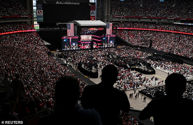 People watch as U.S. President Donald Trump appears on giant screens during a memorial service for slain conservative commentator Charlie Kirk at State Farm Stadium in Glendale, Arizona, U.S., September 21, 2025. REUTERS/Callaghan O'Hare