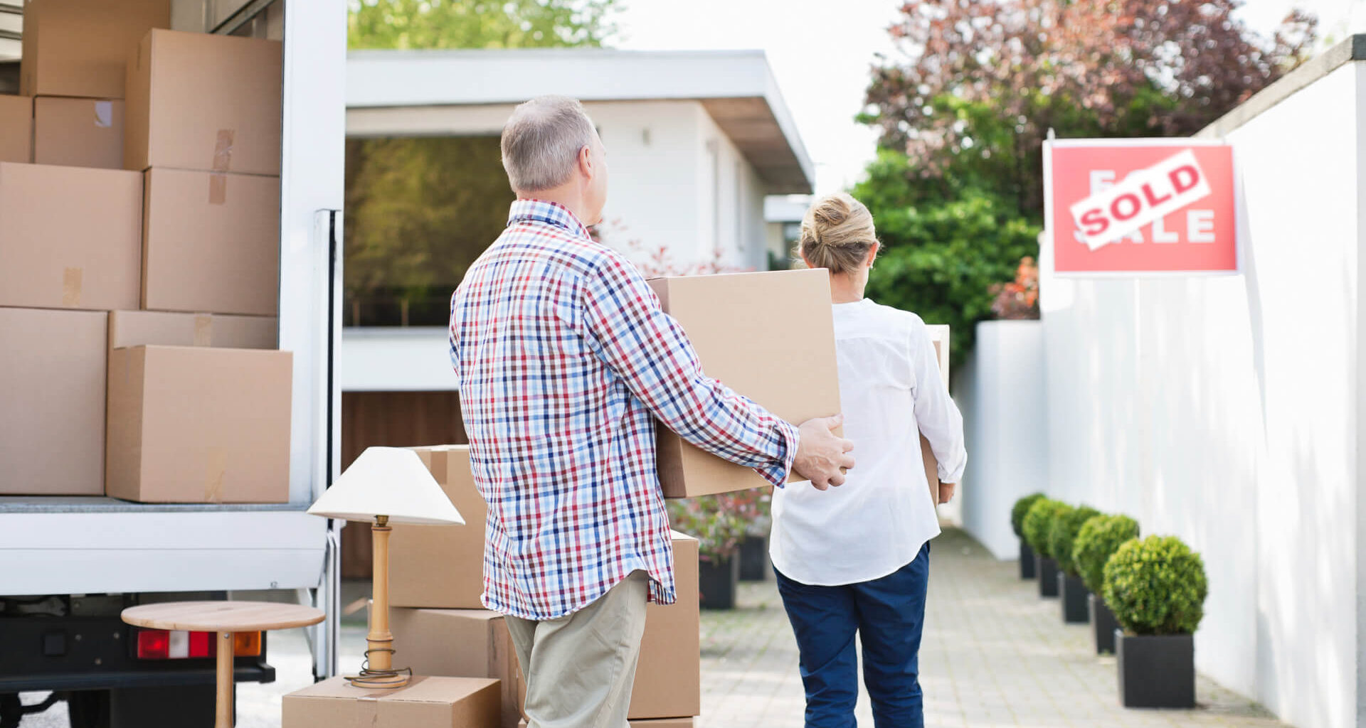 Couple unloading boxes from moving van.