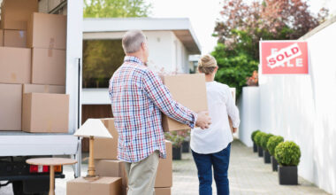 Couple unloading boxes from moving van.