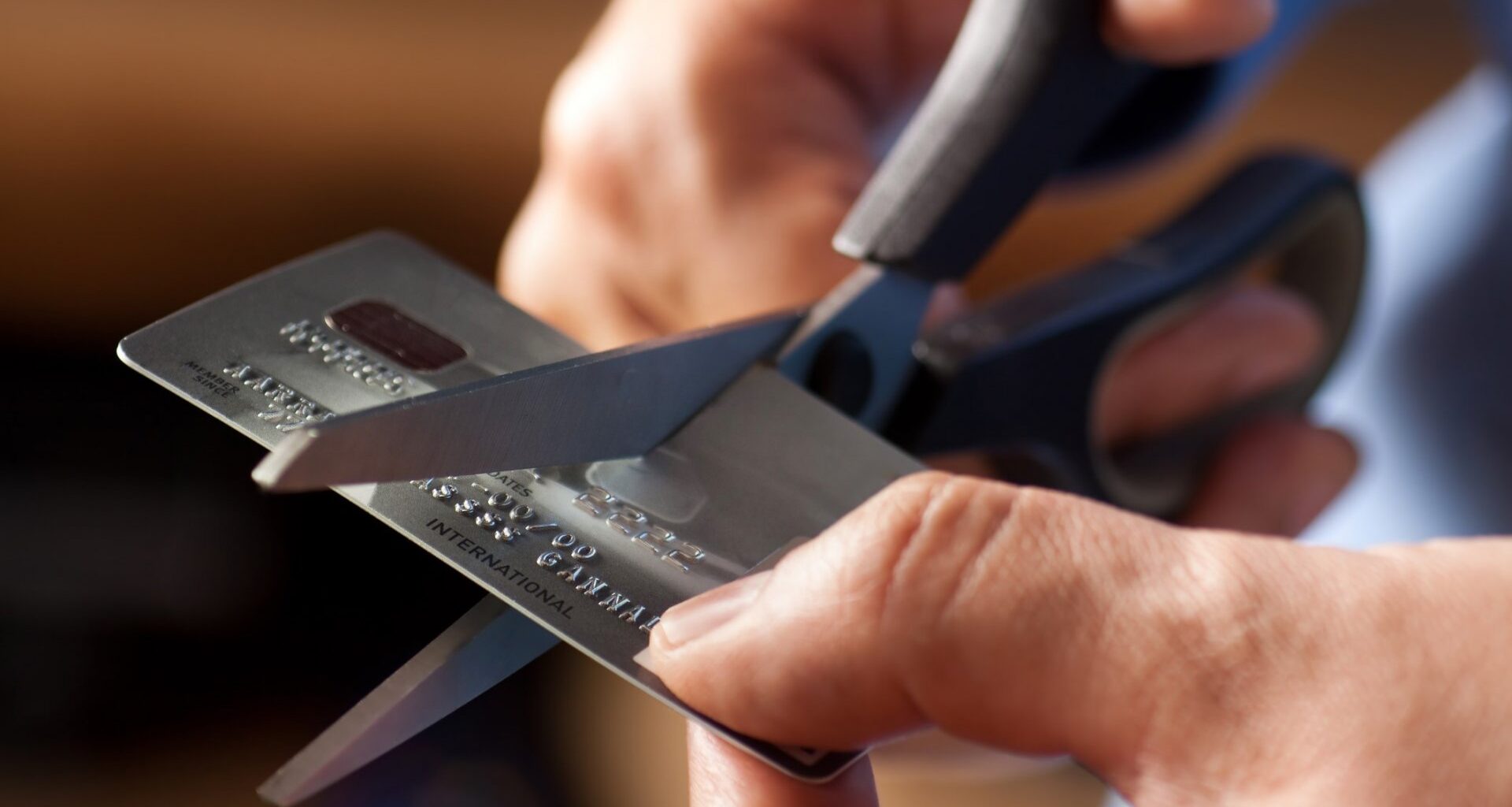 Male hands cutting a credit card with scissors.