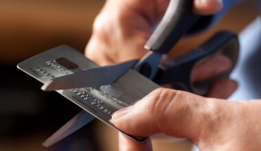 Male hands cutting a credit card with scissors.