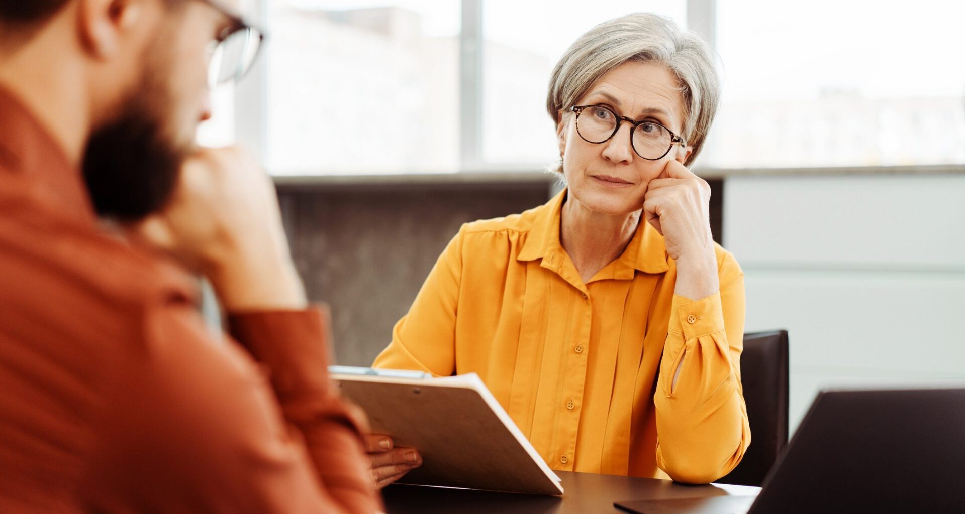 Serious senior woman, psychologist listening patient, looking for solution in modern office.
