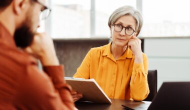 Serious senior woman, psychologist listening patient, looking for solution in modern office.