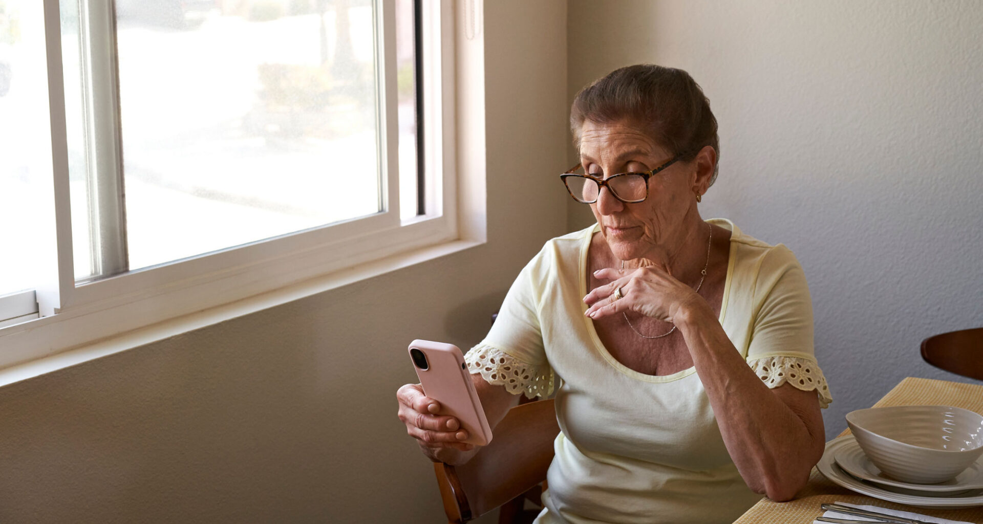 Woman sitting at a table and looking at her cell phone