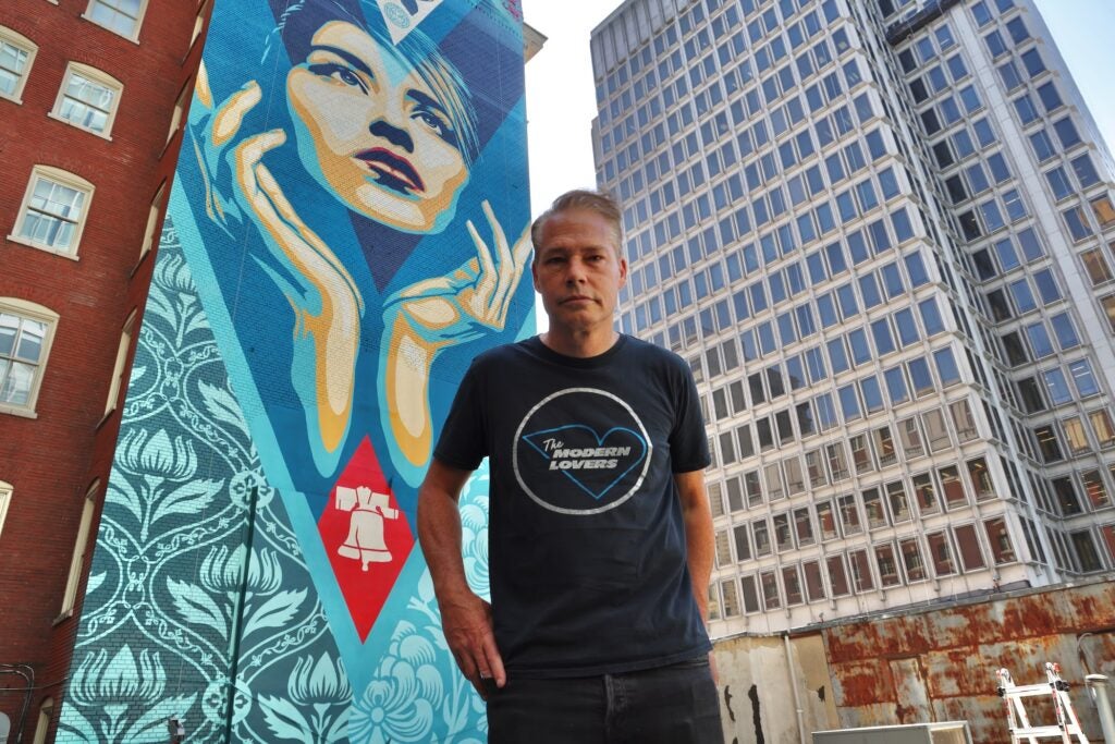 Shepard Fairey stands on a rooftop beside his new mural, ''Uplife Justice.''