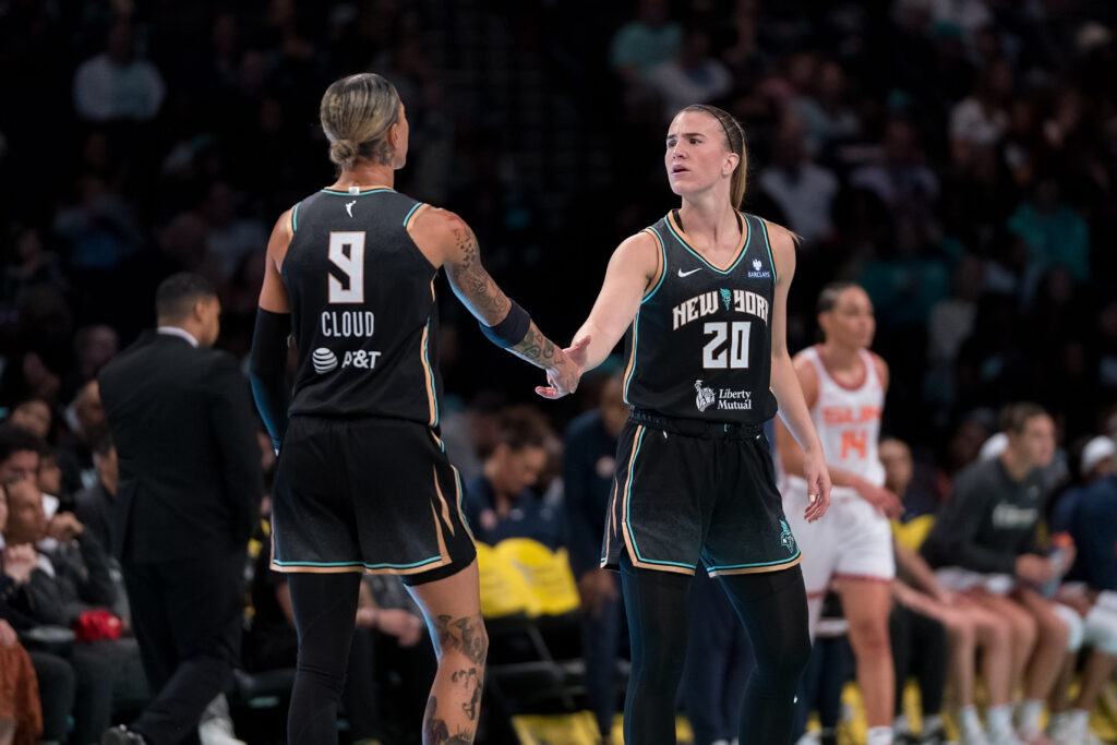 Cloud and Ionescu lightly dap each other up during a game.