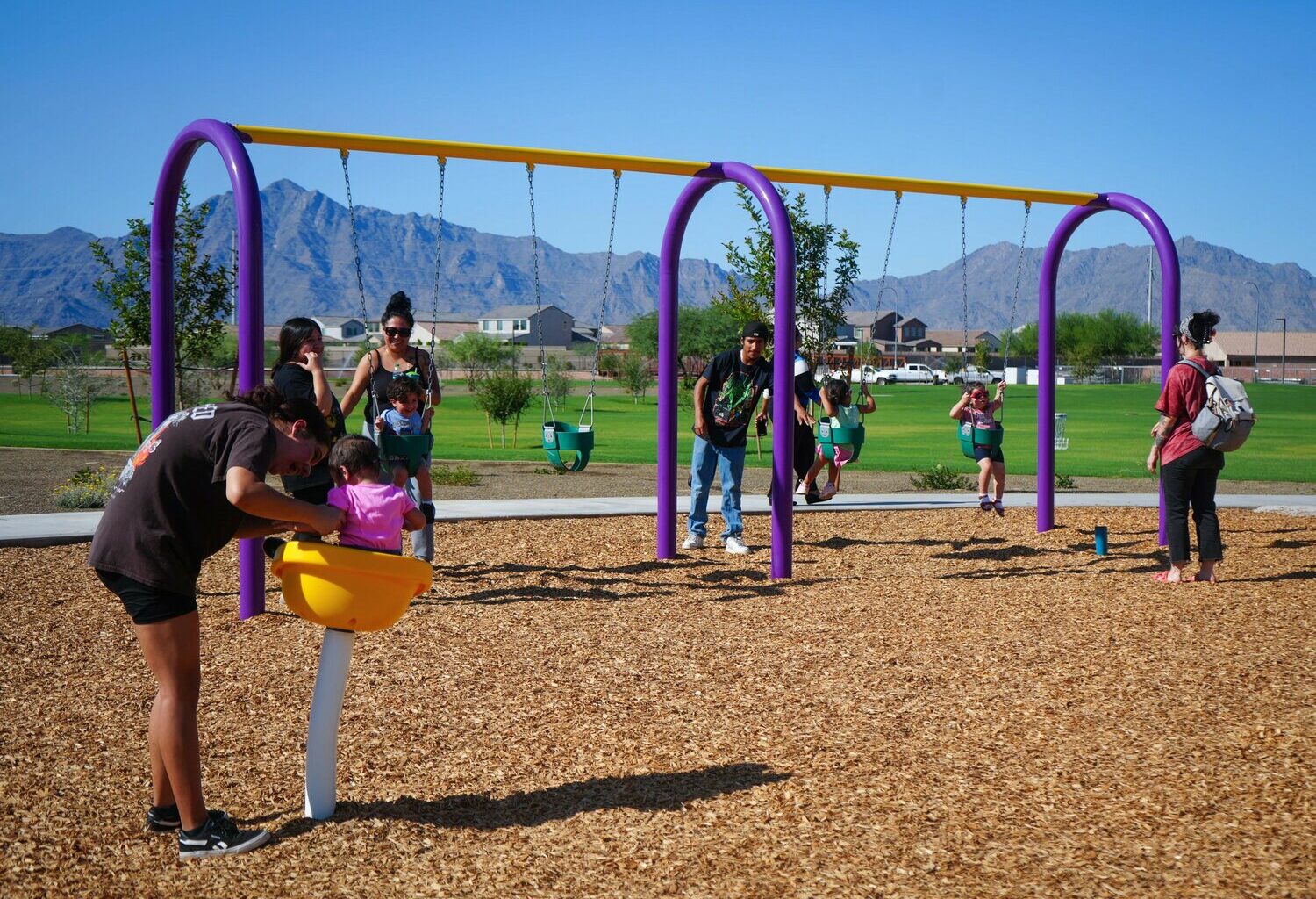 Families play on the swings and other playground equipment during the ribbon-cutting for the new Laveen Heritage Park at 71st Avenue and Meadow Loop Road on Monday, Sept. 8.