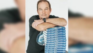 man leans on a stack of books