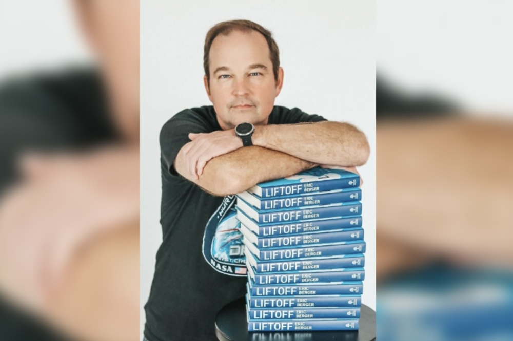 man leans on a stack of books