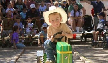 A child rides a toy tractor at a race at the county fair.