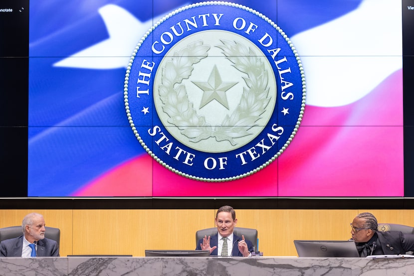 Dallas County Judge Clay Lewis Jenkins, center, runs interference between commissioners...